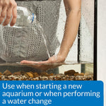 Hand pours clear water into aquarium tank; Aquarium Salt treatment use.