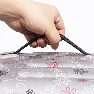 Hand pulling zipper on pet carrier cover with floral fabric, close-up