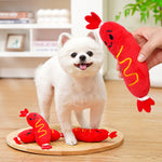 Red plush hot-dog toy with cartoon face, yellow letters and white belly trim