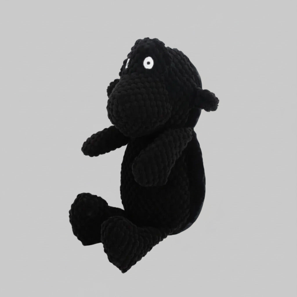 Black plush animal toy with round white eye detail, textured knit fabric, sitting pose