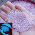 Purple luminous glowing stones, small faceted pieces held in an open hand