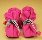 Pink soft dog boots with lace-up cords and red pull tabs