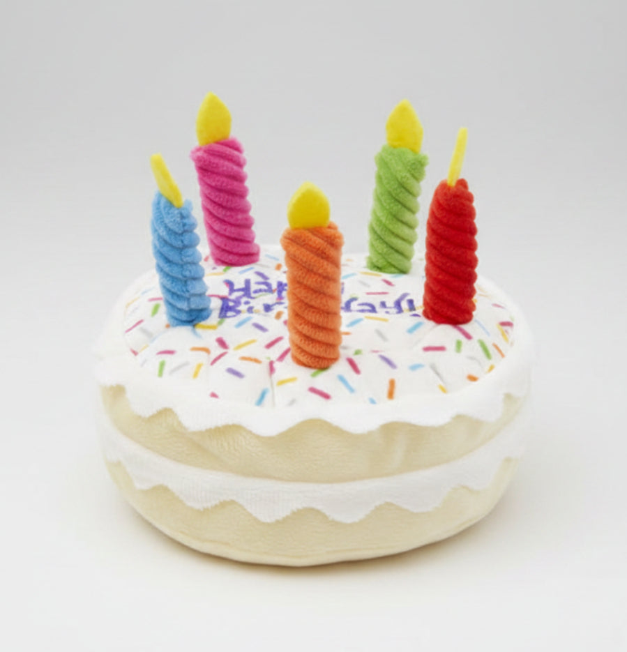 Plush birthday dog toy cake with blue, pink, orange, and green candles and sprinkles