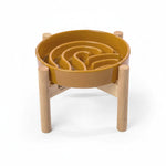 Orange wave slow feeder dog bowl on a wood stand with raised channels