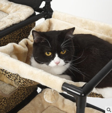 Cat resting on leopard-print plush bed inside climbing tree condo frame.