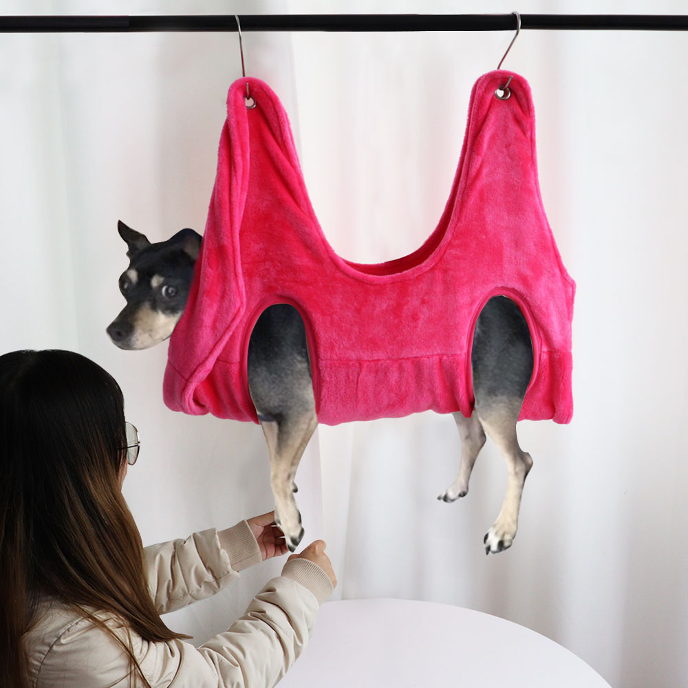Pink pet grooming hammock restraint bag hanging from bar, four leg openings