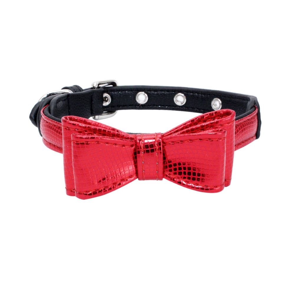 Black pet collar with red bow, crocodile-textured look, and silver grommet studs