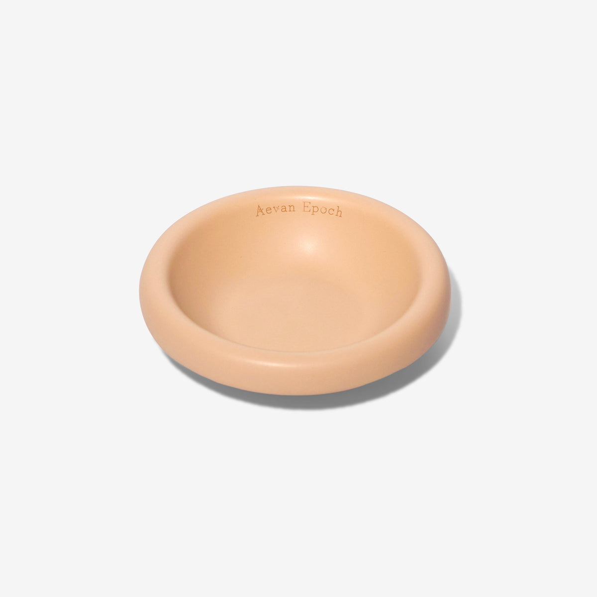 Stoneware pet bowl in light peach, round shallow dish with raised rim and glossy finish.