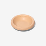Stoneware pet bowl in light peach, round shallow dish with raised rim and glossy finish.