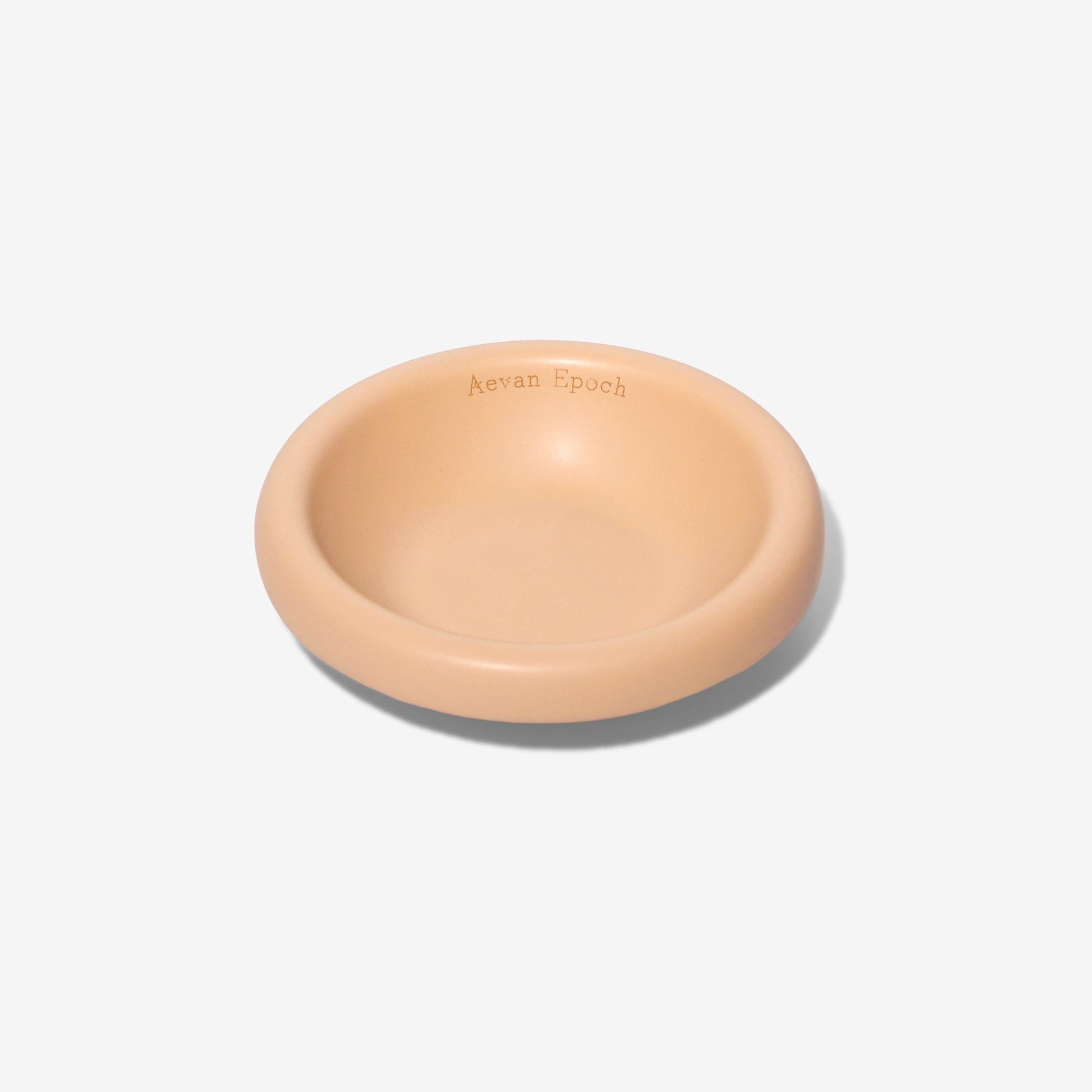 Stoneware pet bowl in light peach, round shallow dish with raised rim and glossy finish.