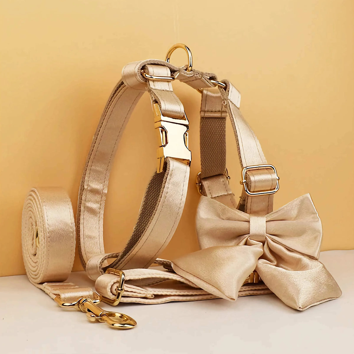 Gold satin dog bow collar set with leash roll, harness straps, and gold hardware