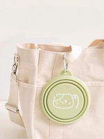 Green foldable pet travel bowl with dog icon, clipped to a canvas tote