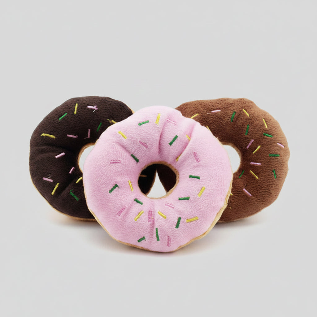 Plush donut dog toys in dark brown, pink, and brown with sprinkles and center hole