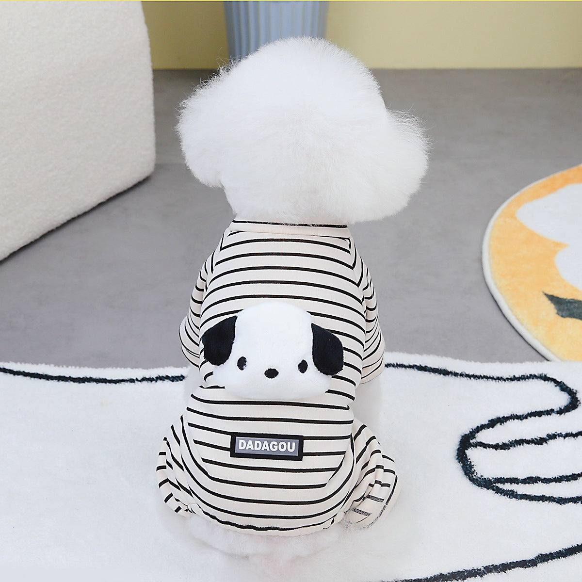 White fluffy dog wearing black-and-white striped two-leg panda sweater with hood