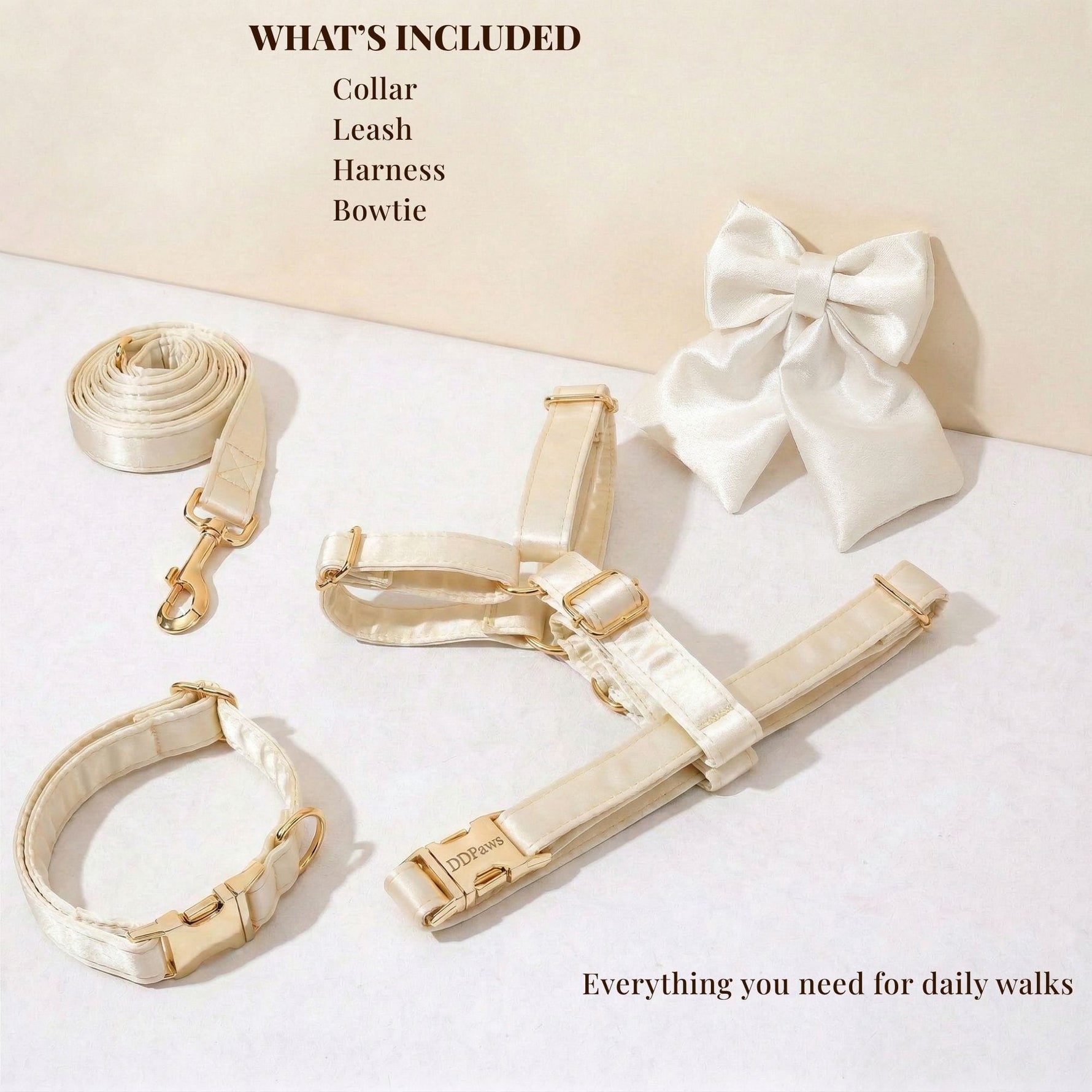 White satin collar, leash, harness, and bowtie with gold clips laid out