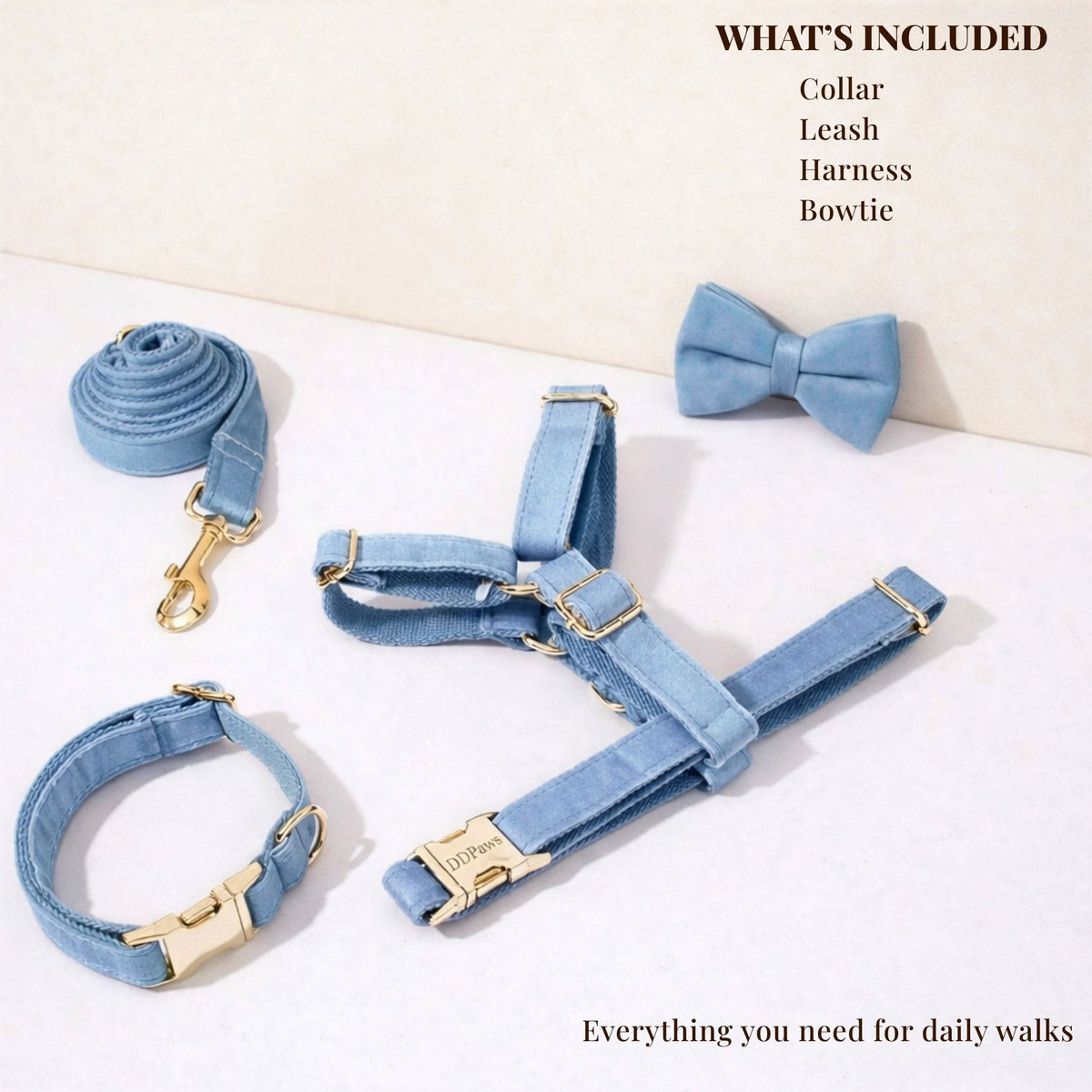 Blue denim dog collar, leash, harness, and bowtie set laid out with gold clips