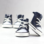 Pair of navy canvas dog shoes with white laces and striped rubber soles
