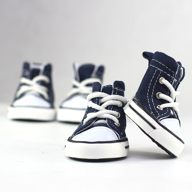 Pair of navy canvas dog shoes with white laces and striped rubber soles