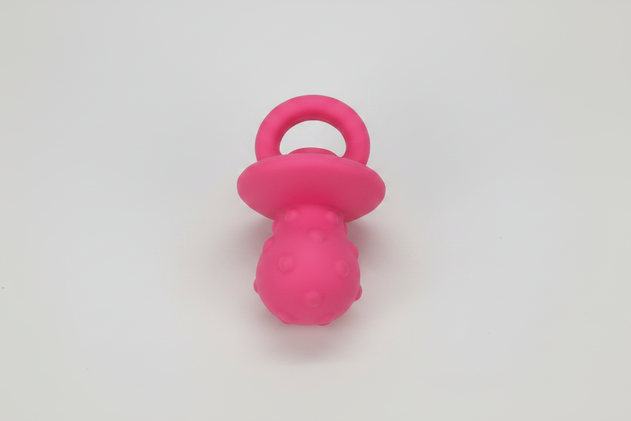 Latex squeaky pacifier dog toy in pink, with ring handle and textured bulb