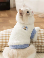 White plush pet sweater with light-blue cuffs and cute patch badge