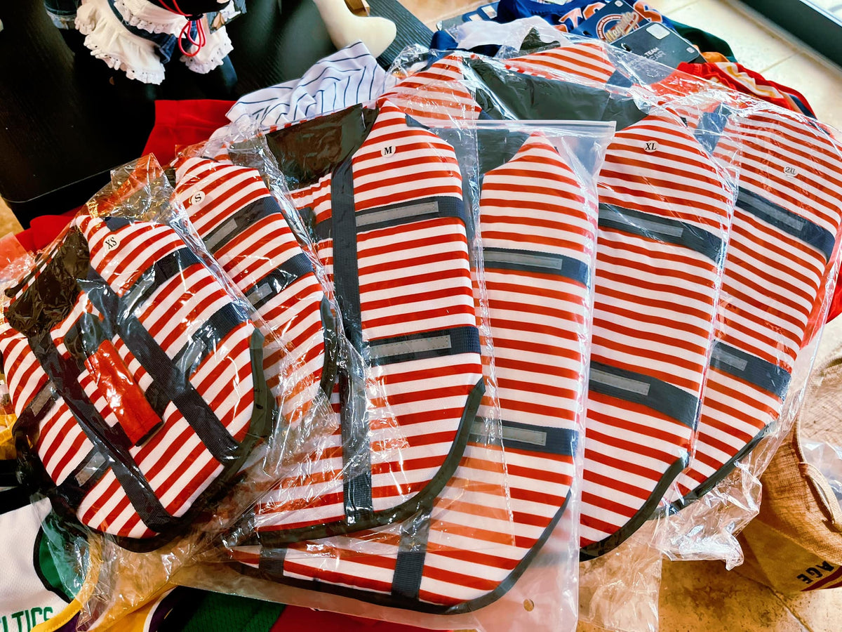 Pack of striped dog life jackets in plastic bags, red white navy with safety straps