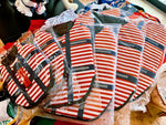 Pack of striped dog life jackets in plastic bags, red white navy with safety straps