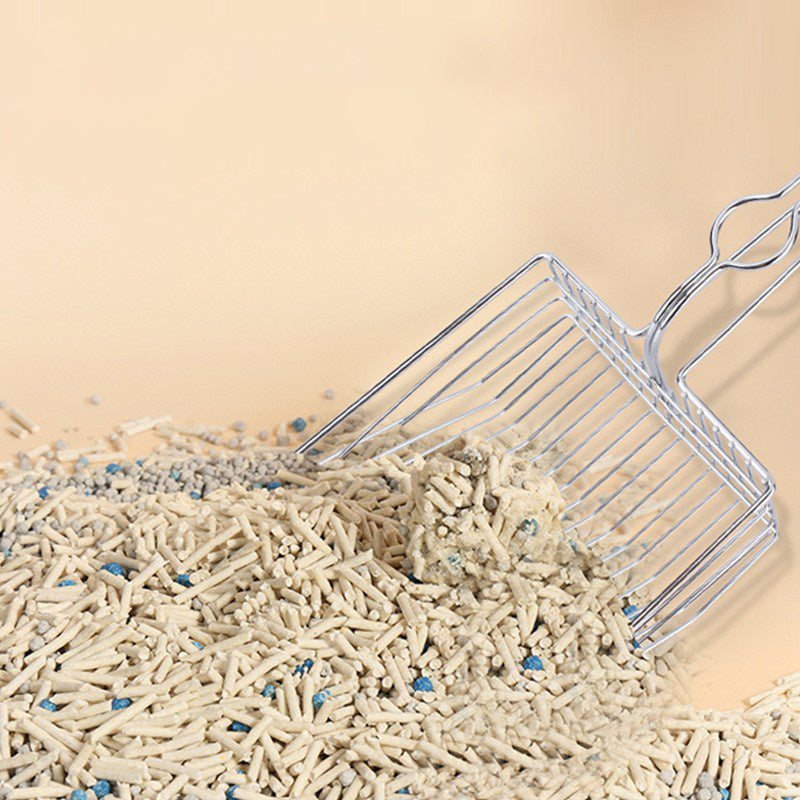 Wire mesh litter scoop resting in pellets, with loop handle