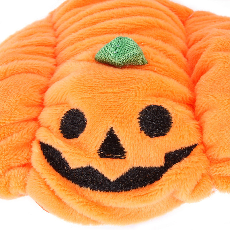 Close-up pumpkin pet hat: orange plush with stitched jack-o-lantern smile and green stem