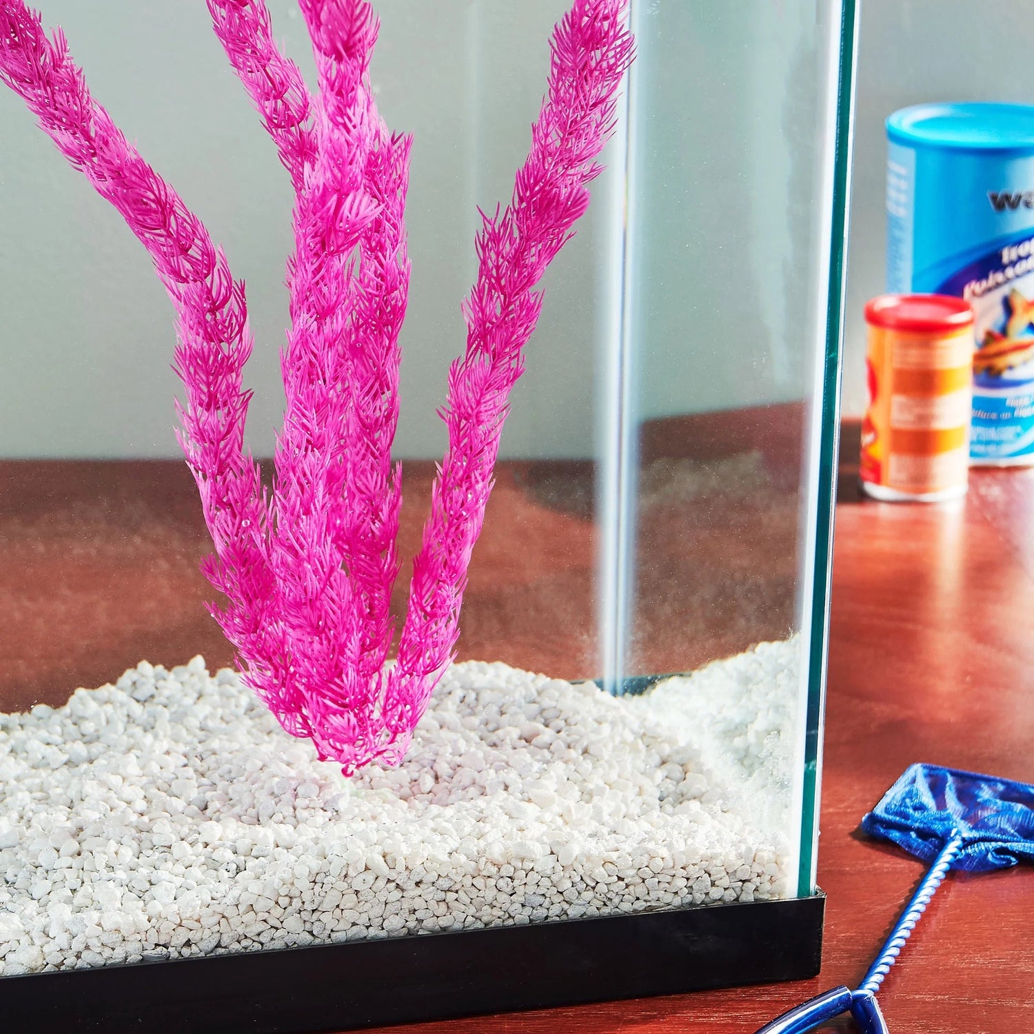 Pink artificial aquarium plant with tall fronds on gravel
