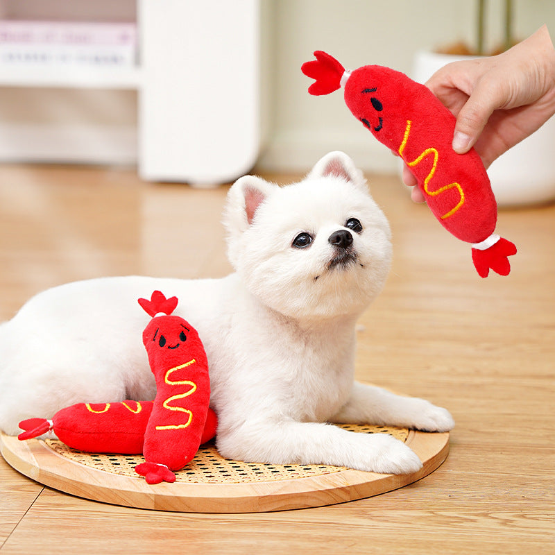 Red plush hot-dog toy held in hand, cartoon face and yellow stitched letters