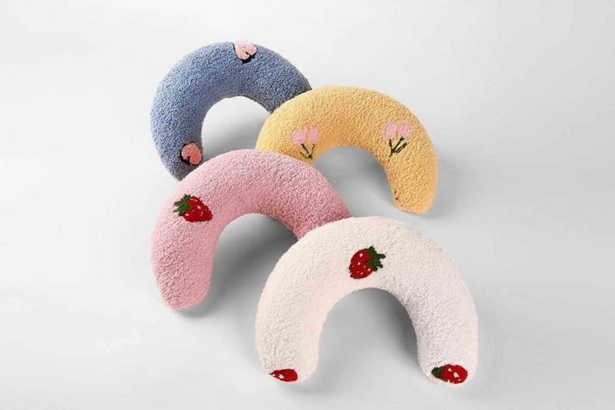 Plush U-shaped cat pillow toys set: blue, tan, pink, and white with small fruit patches