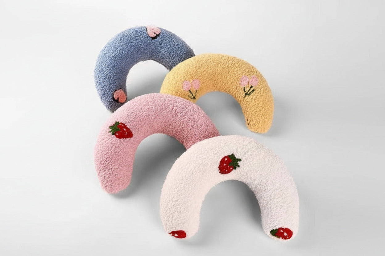 Plush U-shaped cat pillow toys set: blue, tan, pink, and white with small fruit patches
