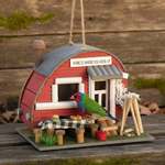 Red trailer birdhouse with awning, porch details, and green bird at the door