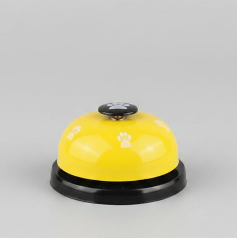 Yellow paw press pet training bell with black base and paw-print button