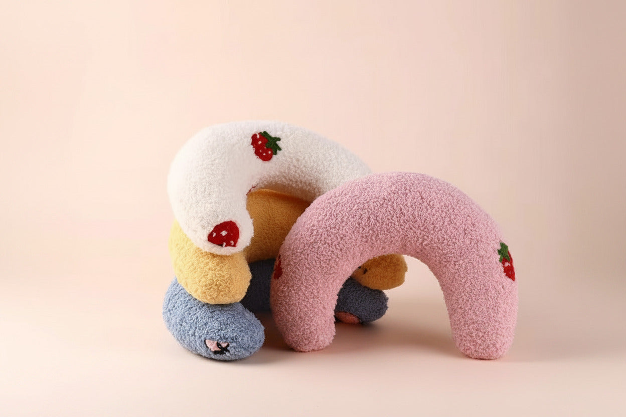 Pink plush U-shaped cat pillow toy with red fruit patches and small matching arches