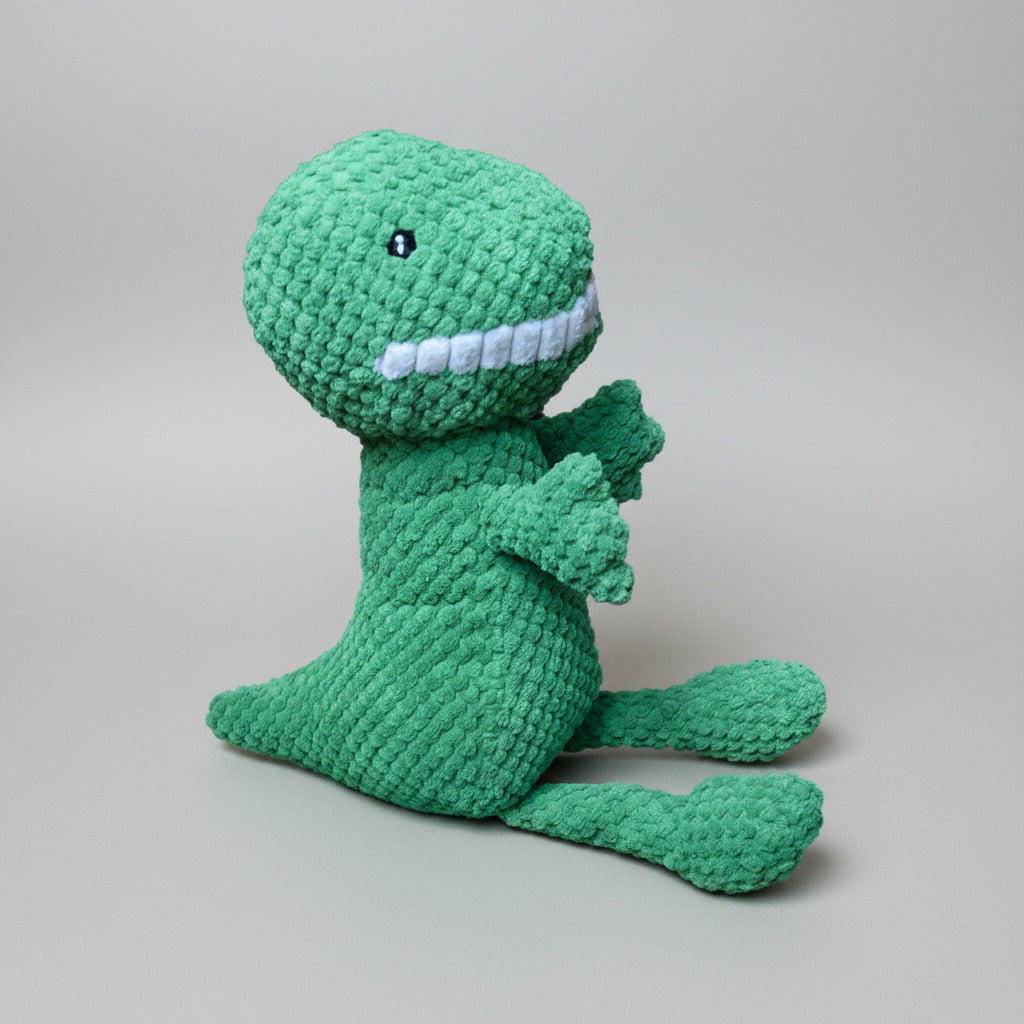 Green dinosaur plush pet toy with white tooth detail and long outstretched tail