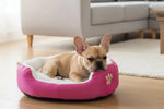 Pink round pet bed with white plush liner and paw emblem, dog sleeping inside