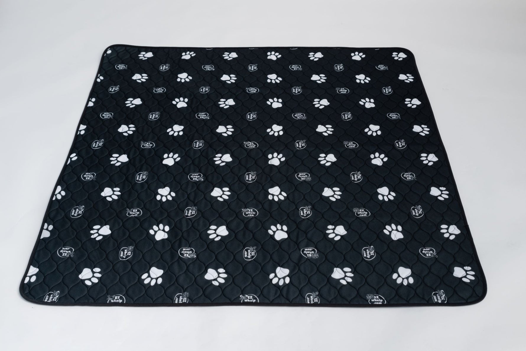 Black pet mat with white paw prints and quilted grip surface