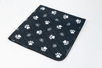 Black pet mat with white paw prints, quilted texture, rounded corner