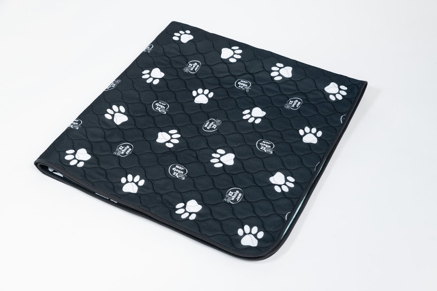 Black pet mat with white paw prints, quilted texture, rounded corner