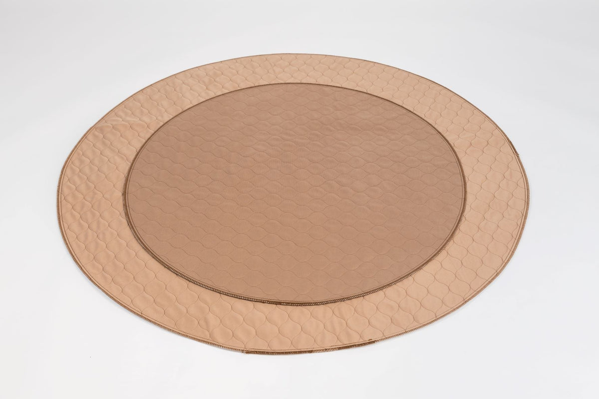 Tan round pet mat with quilted hex pattern, stitched edge