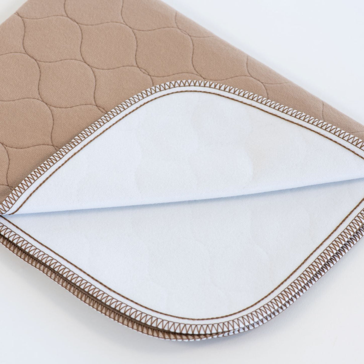 Tan pet mat corner with quilted pattern and stitched seam edge