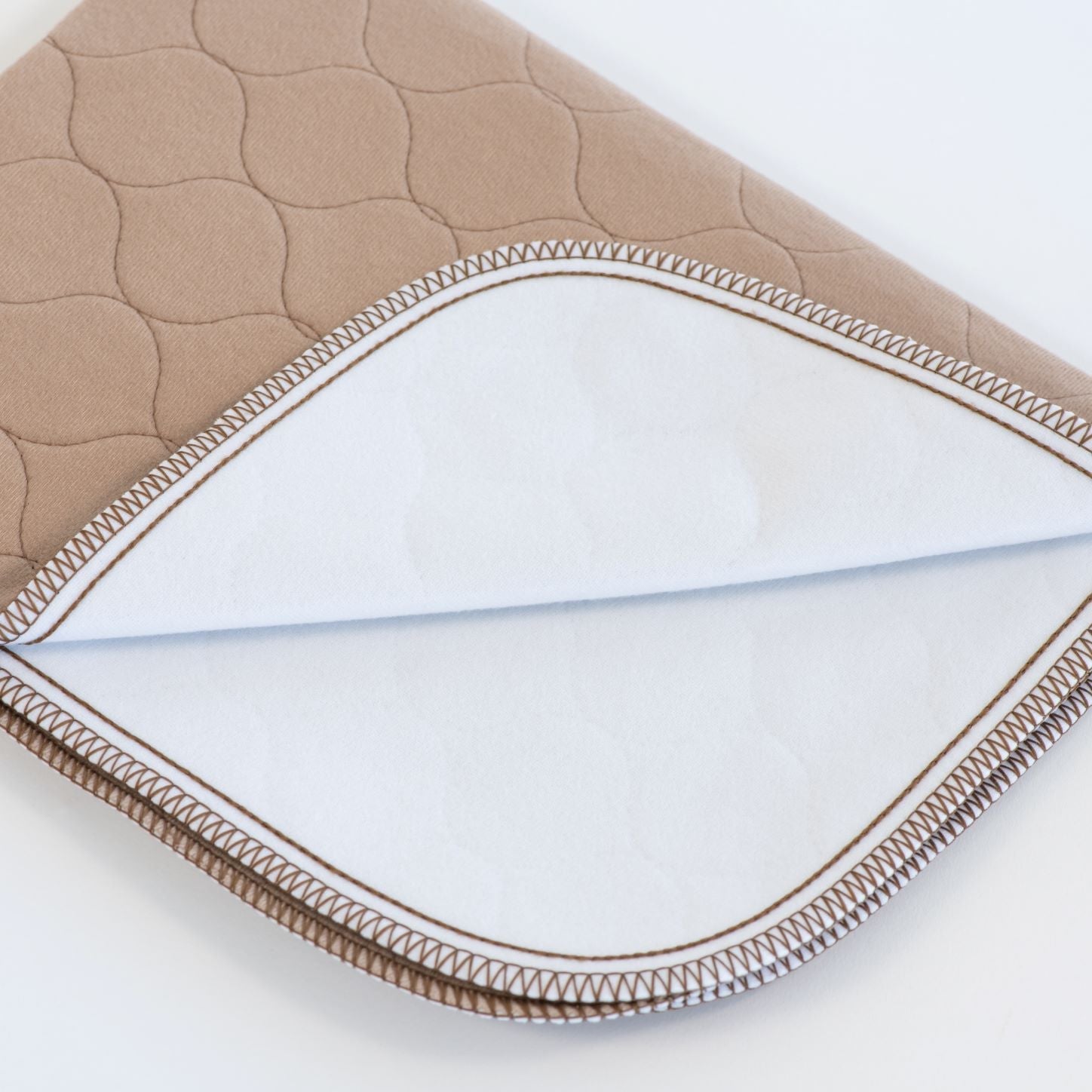 Tan pet mat corner with quilted pattern and stitched seam edge