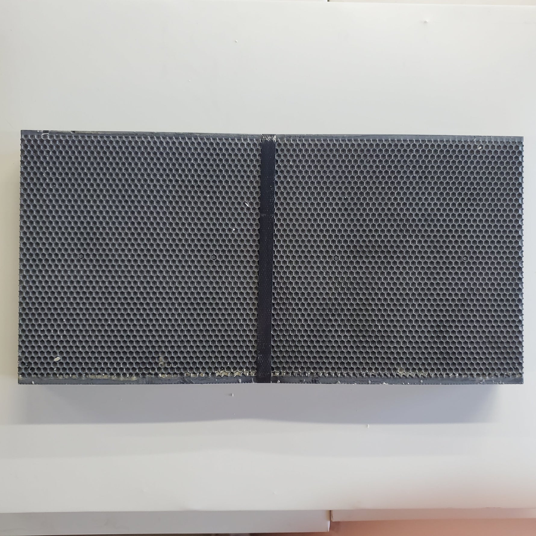 Two dark plastic foundation panels with dense hexagonal pattern