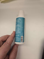 Liquid wormer bottle side view held in hand, white with teal label