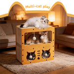 Cardboard cat house with plush ball openings; three cats lounging inside and on top
