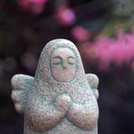 Close-up speckled gray stone guardian ornament with hood and clasped hands
