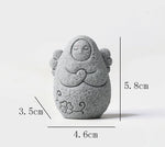 Speckled gray stone guardian ornament with hood, closed eyes, clasped hands
