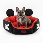Round red-and-black pet bed with Mickey Mouse logo, dark bolsters, with a French bulldog inside