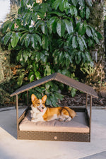 Outdoor pet cabana bed with beige cushion and tan-and-white corgi resting inside